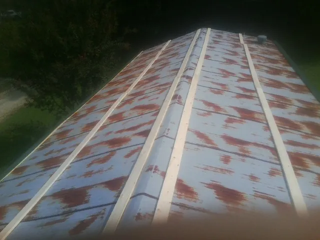Rusted metal roof panels with new wood purlins before replacement — Storm Damage Roof Repair in Champlain by Roofing Brothers