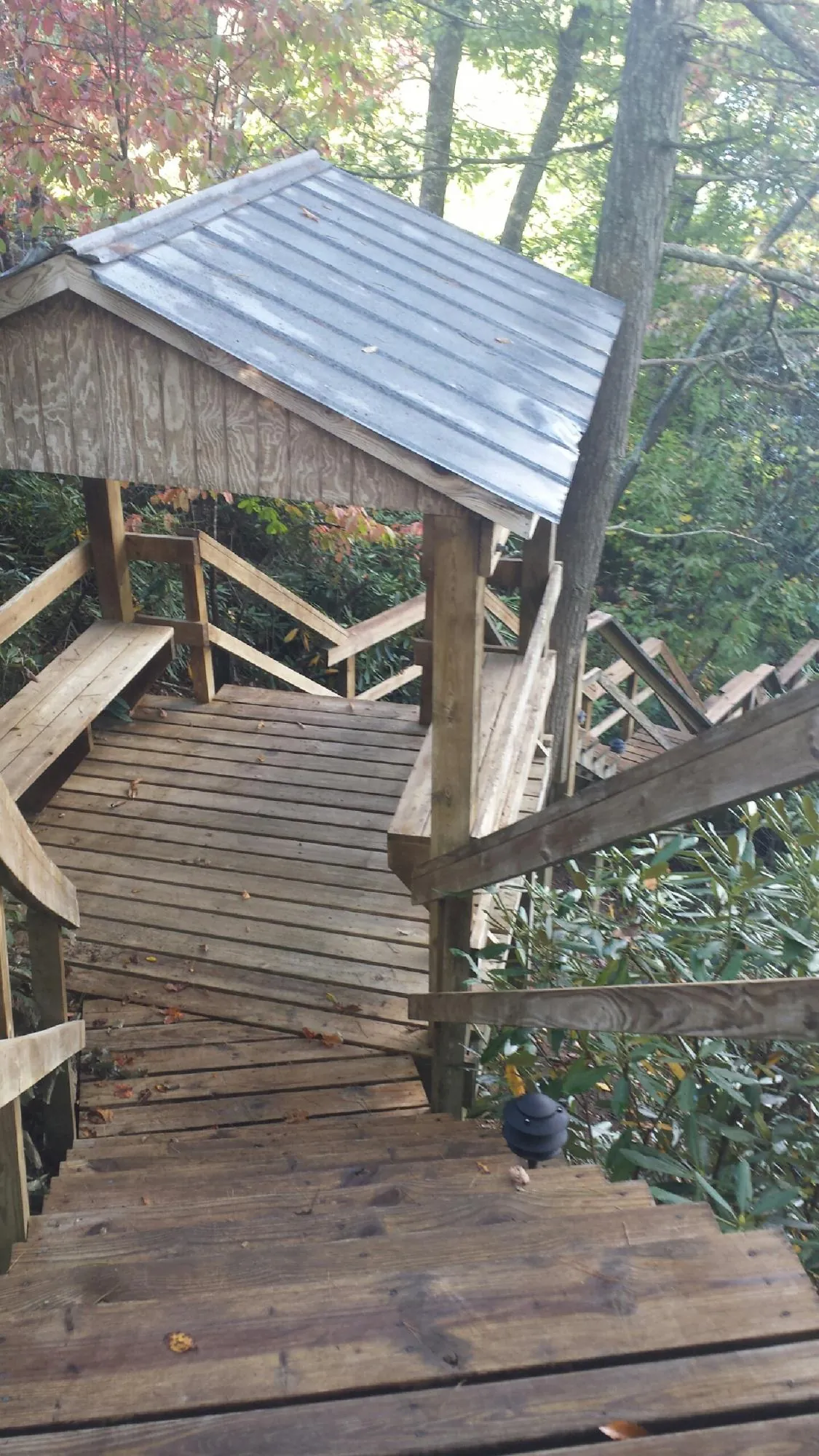Metal roofed shelter over wooden steps on a wooded walkway — Skylight Repair & Installation work by our crew in Champlain