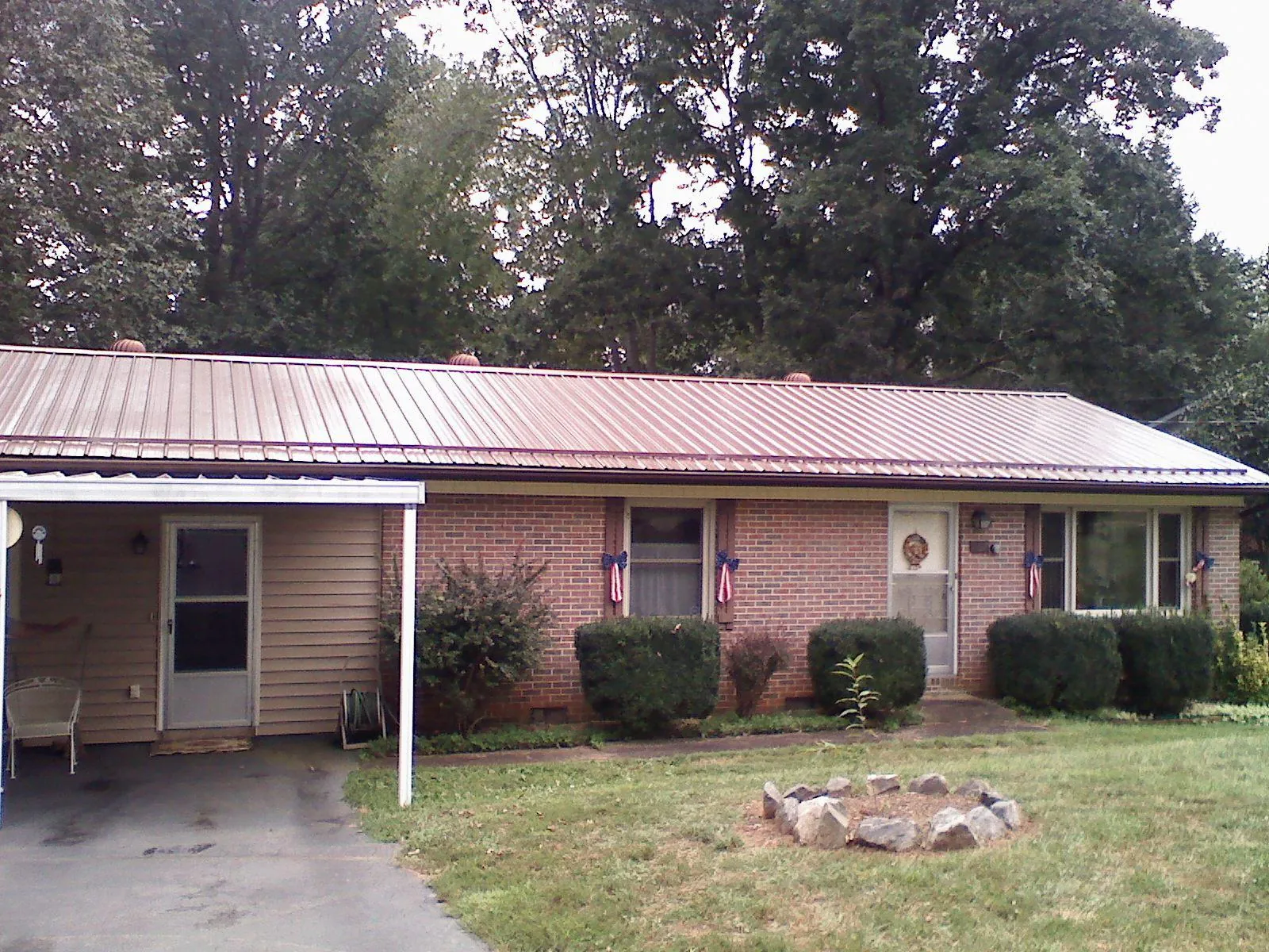 Bronze metal roof and carport on a brick ranch home — Roof Repair work by our crew in Champlain